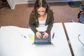 En tjej som sitter vid en laptop och jobbar.