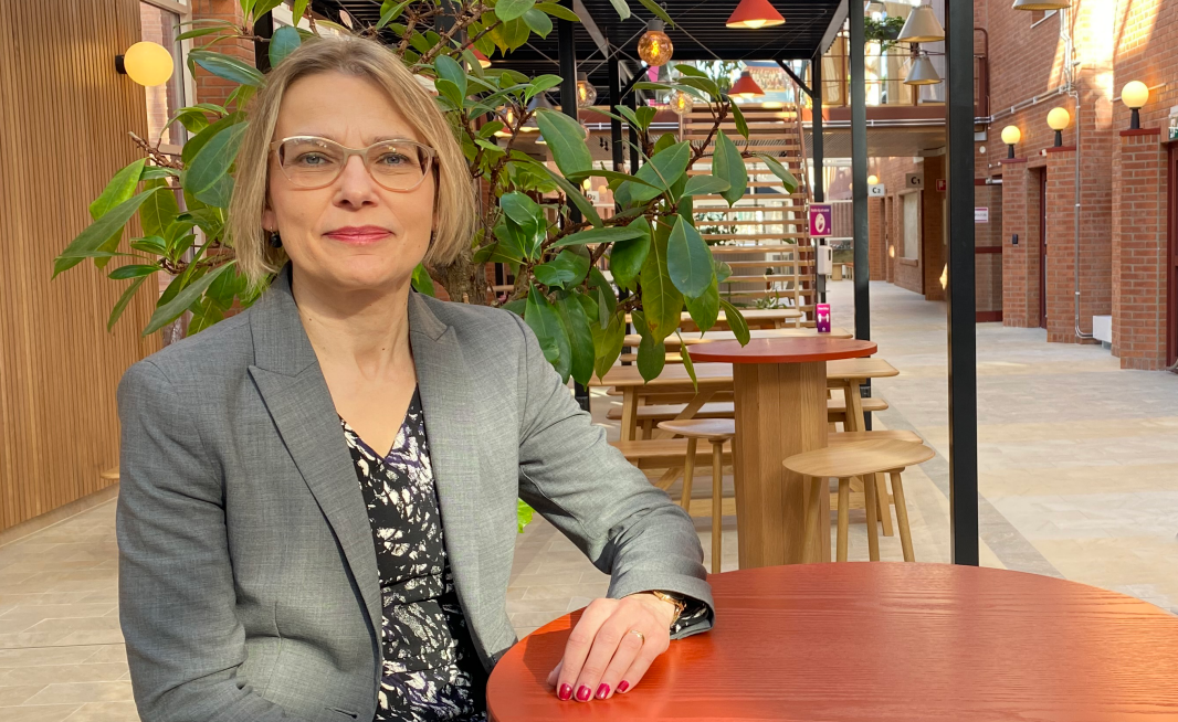 Maria Jansdotter Samuelsson sitter vid ett cafébord i ljusgården på Campus Falun. 