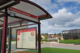 Högskolan Dalarna byggnad och grönskande utomhusmiljö på Campus Falun samt busskur