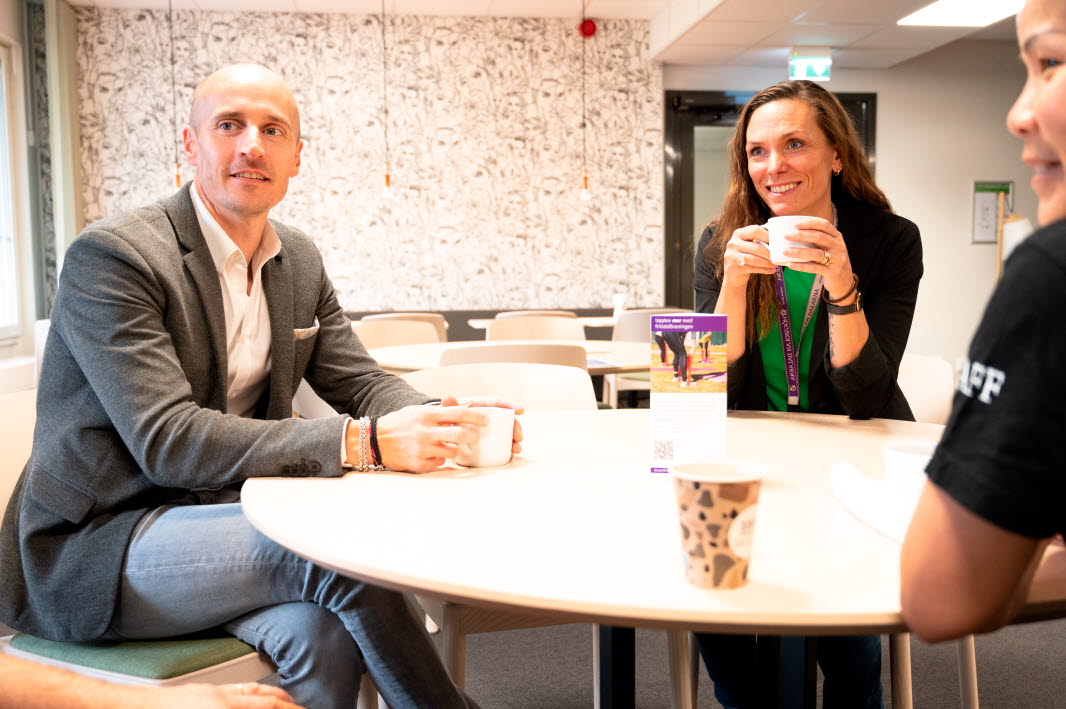 Tre personer sitter vid ett runt bord med kaffekoppar framför sig. Personerna ser glada ut. Anvisningar för användning	