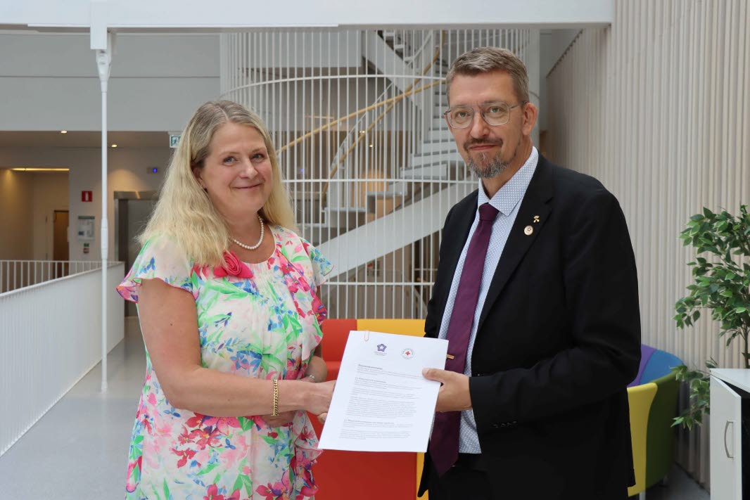 Susanne Georgsson, rektor vid Röda Korsets Högskola och Martin Norsell, rektor Högskolan Dalarna håller i ett papper tillsammans.