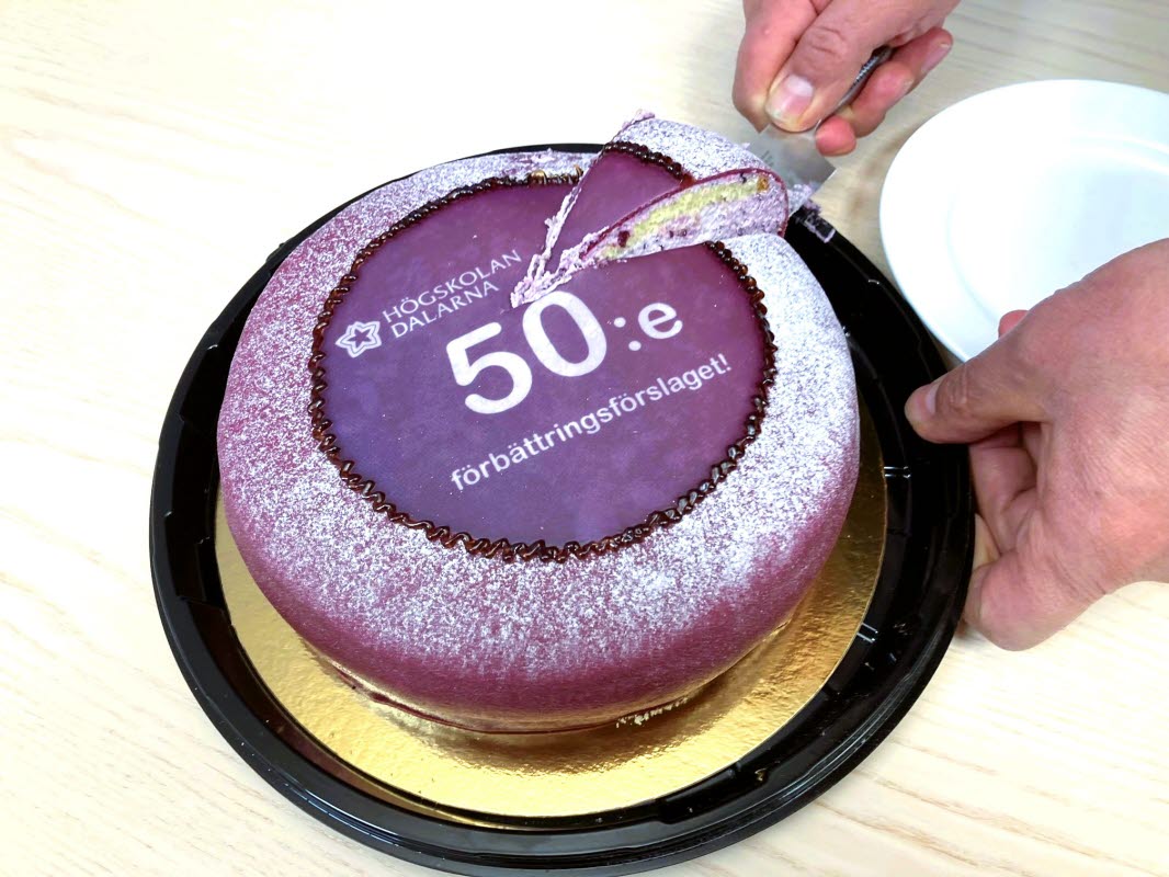 En lila prinsesstårta på ett guldfat. Tårtan tar texten "50:e" på sig.