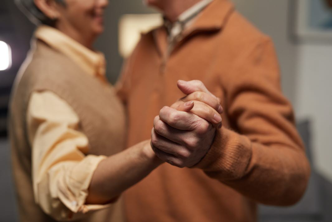 Äldre par håller hand dansar inomhus