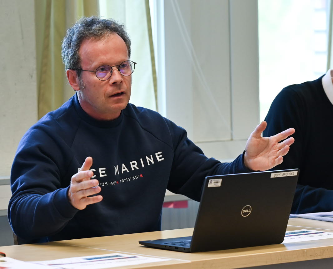 Michail Tonkonogi sitter vid ett bord med en dator framför sig och gestikulerar.