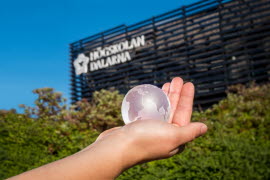 Jordglob av glas handen framför byggnaden Campus Falun. 