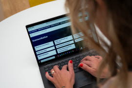 En kvinna sitter vid en bärbar dator.