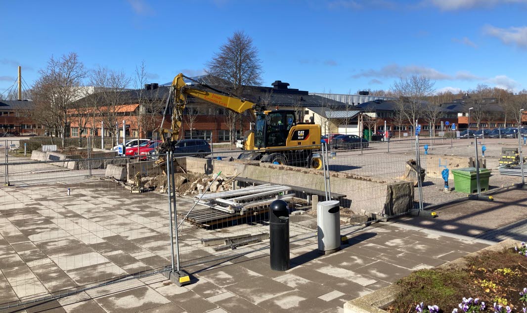  An excavator breaks up tiles in the road.