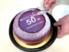En lila prinsesstårta på ett guldfat. Tårtan tar texten "50:e" på sig.